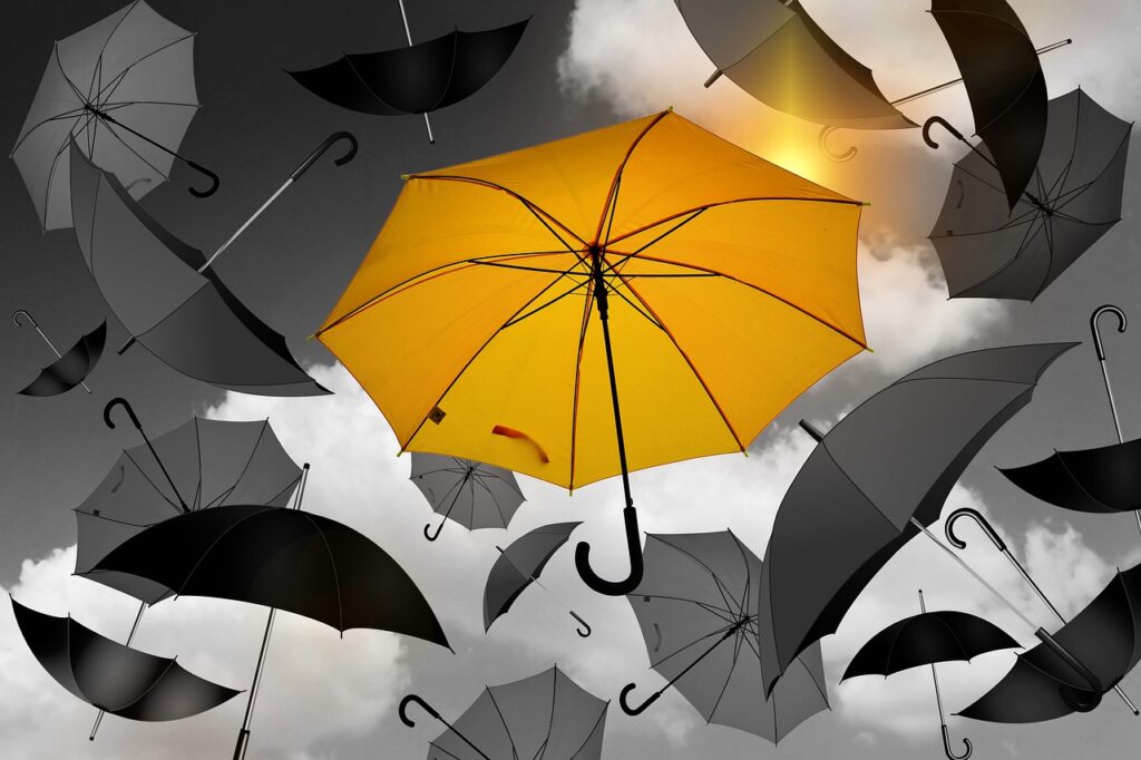 A yellow umbrella mixed with black and grey umbrelllas