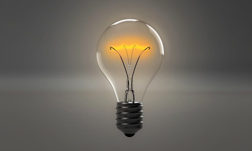 A dimly lit light bulb on a grey background